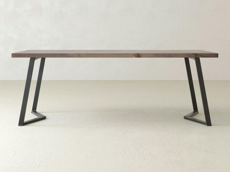 The Arkwright Desk by James+James is a minimalist modern table with a rectangular wooden top and angular, black metal legs. Set against a light-colored background, its industrial flair and sleek design create an ideal solid workspace for any setting.