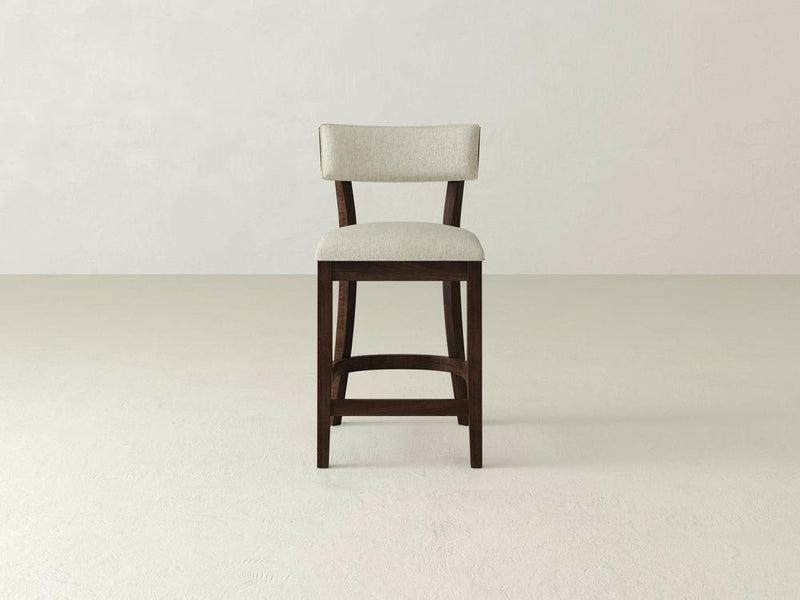 The Everly Upholstered Stool by James & James features a high-backed wooden design with a light-colored upholstered seat and backrest, showcasing mid-century charm against a plain, light background.