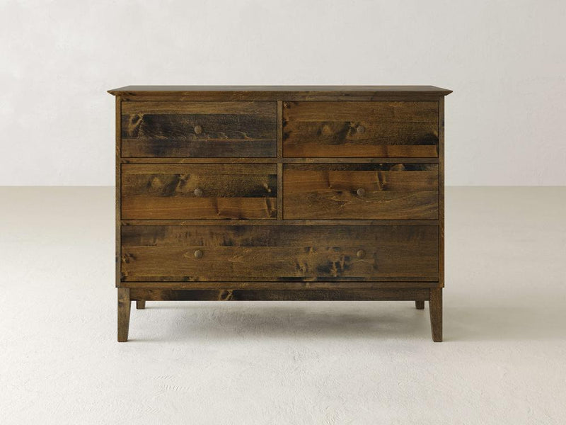 The Bennett 5 Drawer Dresser by James & James, crafted from solid maple wood, stands against a plain light-colored background. This piece showcases a traditional design with rustic charm and round knobs on each of its five drawers.