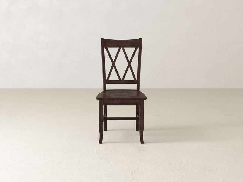 A wooden chair with a dark brown finish stands against a plain white background. The chair features a crisscross backrest design, a flat seat, and four straight legs.