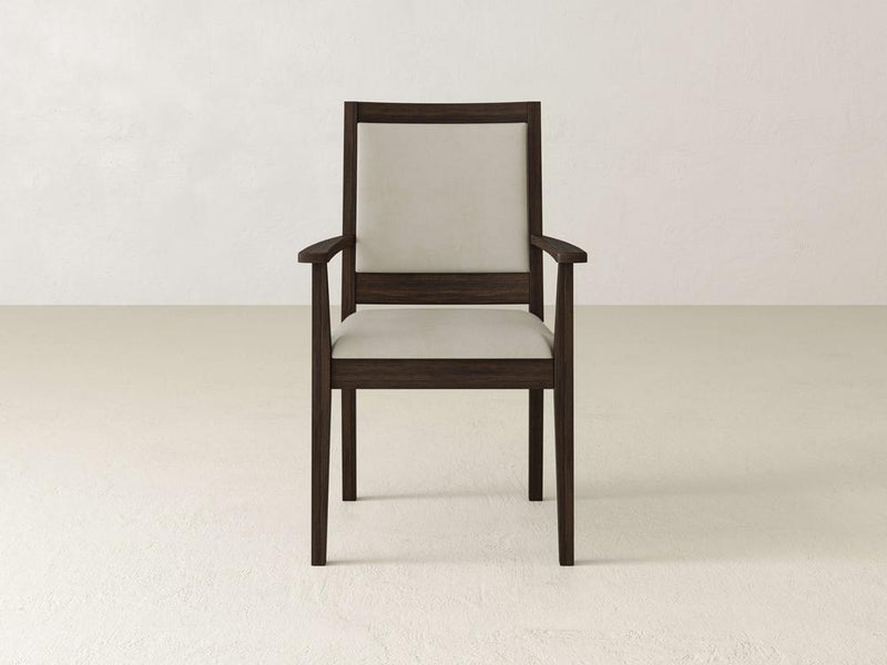 A wooden chair with a brown frame and light beige cushion is centered against a plain, light-colored background. The chair has armrests and a high backrest, featuring a simple, minimalist design.