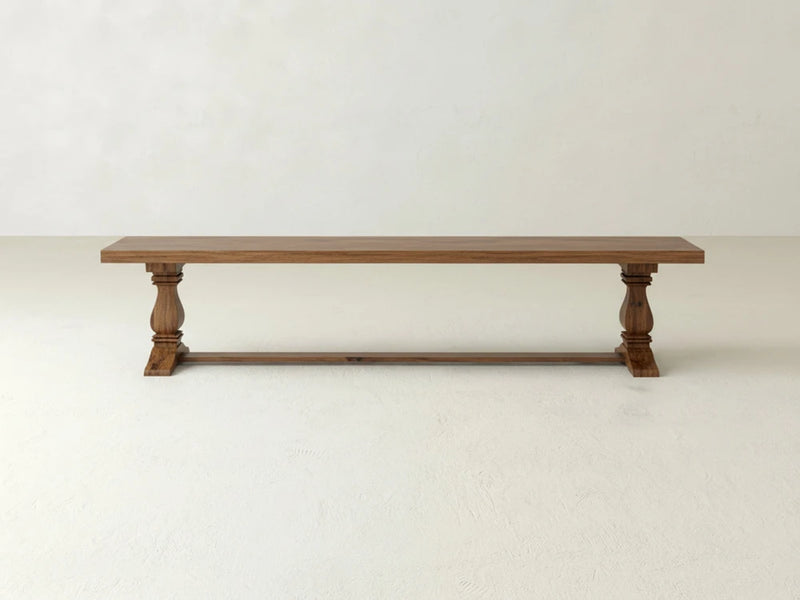 The Heirloom Bench - Almond on Oak by James+James features a flat wooden seat and two carved legs, shown against a plain white background.