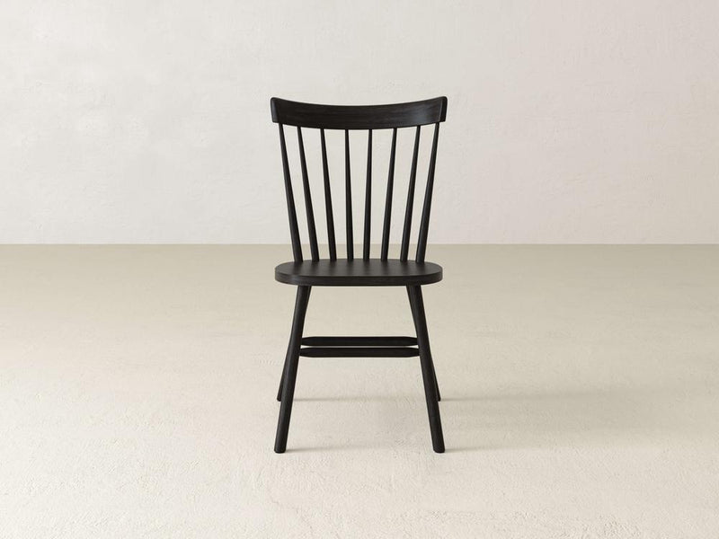 A dark wooden chair with a curved backrest, featuring vertical slats, four legs, and a rounded seat, is shown against a plain white background.
