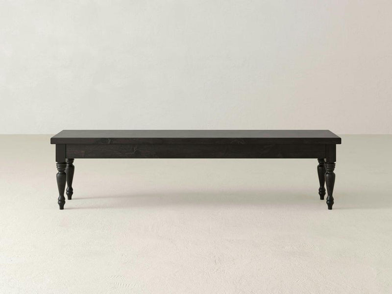 The Chateau Bench - Charred Ember by James & James, with its dark wood and turned legs, rests on a light floor against a plain wall, highlighting its minimalist rectangular design.