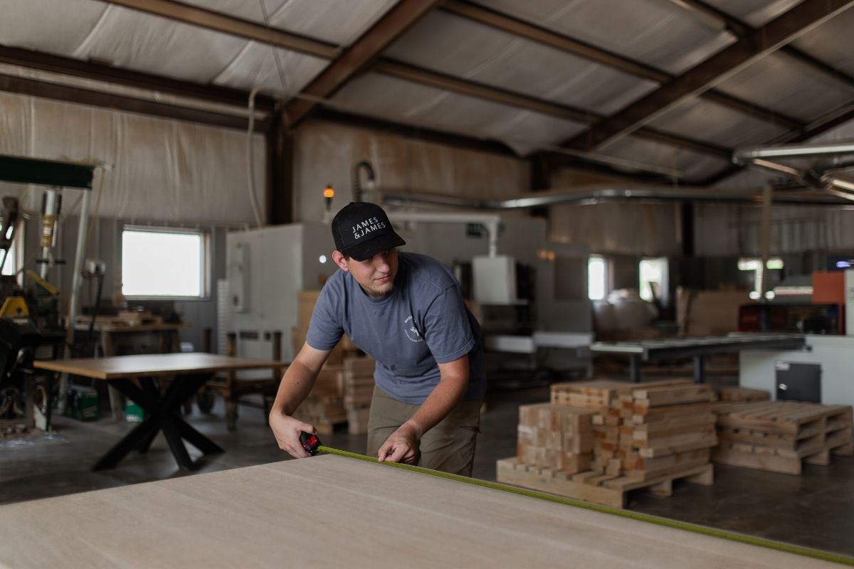 Craftsman at James & James measuring wood in the workshop, showing the custom furniture process that elevates high-end residential projects.  
