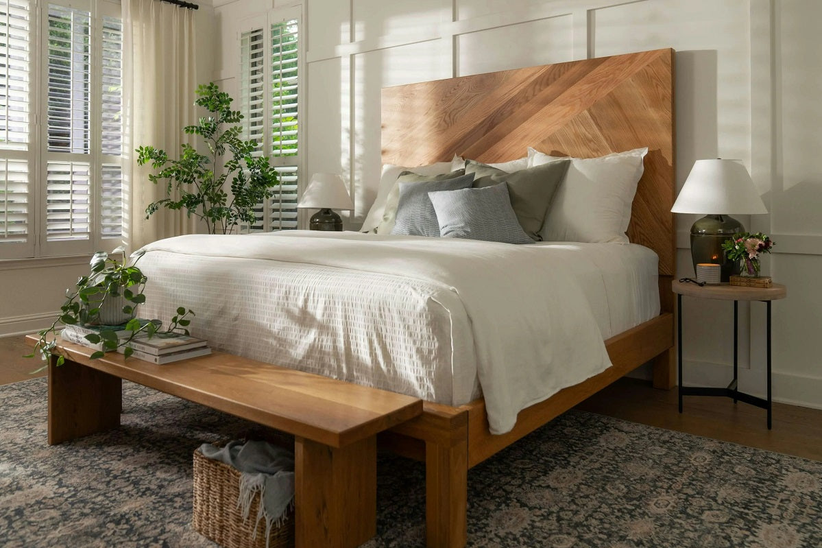 Solid wood bed frame with chevron headboard in a bright bedroom, illustrating size and design considerations when choosing between twin and twin XL beds.  