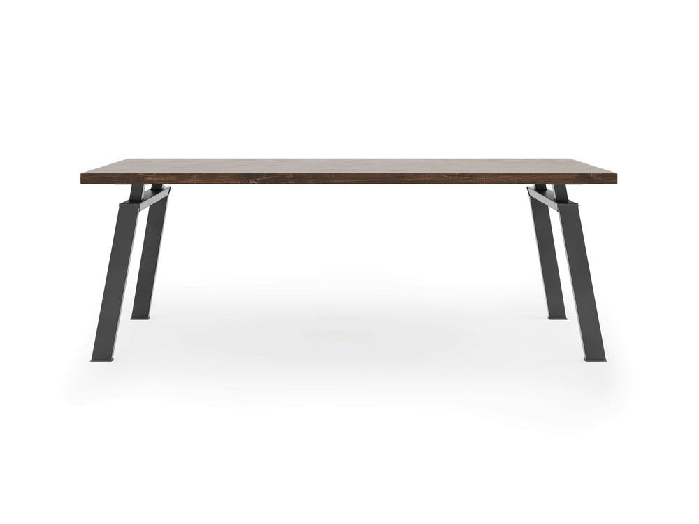 The Fulton Desk - Tobacco by James+James features a rectangular dark wooden top with black metal legs. The angled legs offer sturdy support, complementing the sleek tabletop. Its modern and minimalist design makes it an ideal choice for various settings, such as dining rooms, offices, or workspaces.