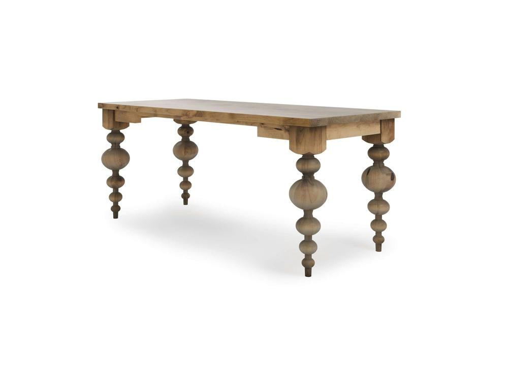 The Olivia Desk in Harvest Wheat by James+James features a rectangular top and four intricately carved legs with large circular accents. This desk boasts a rustic finish that beautifully highlights the natural grain and texture of the wood.