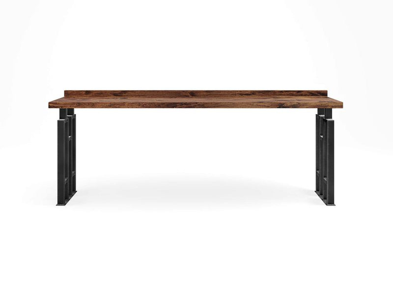 The Clark Sofa Table - Tuscany by James+James showcases a minimalist wooden tabletop adorned with visible grain patterns, elegantly supported by sleek black metal legs. The design exudes a modern and industrial aesthetic, characterized by clean lines and a robust structure.