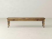 The Chateau Bench - Harvest Wheat by James & James stands against a plain white background, featuring four carved legs and a simple rectangular seat, showcasing its rustic design with a natural wooden finish.