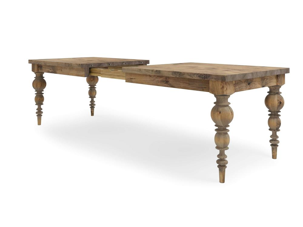 The Bailey Expandable Dining Table by James+James features a long wooden design with ornate, turned legs and a rustic Harvest Wheat finish. The table showcases a split design in the middle, which allows it to be extended with additional leaves or sections. The visible wood grain and texture contribute to its vintage aesthetic.