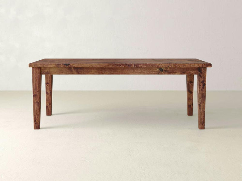 The Ava Parsons Dining Table - Tuscany by James+James stands on a plain white background. This wooden table has a rustic design, featuring a rich, dark wood finish and simple, sturdy construction with four legs.