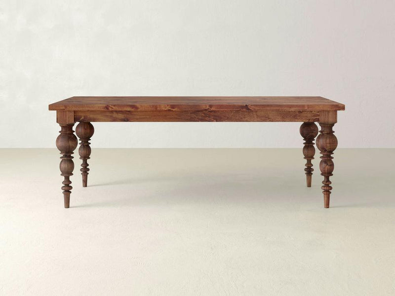 The Bailey Dining Table - Tuscany from James+James features a rectangular top with ornate turned legs, showcasing heirloom-quality design. The rich brown finish contrasts elegantly against a plain, light background, embodying modern elegance.