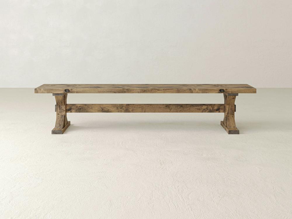 The James+James Trestle Bench in Harvest Wheat on Alder features a simple, sturdy design and rustic wood finish, shown against a plain off-white background.