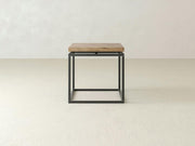 The Floating Top End Table by James+James is a minimalist side table showcasing a hardwood top and a sleek black metal square frame base. Ideal for modern decor, this end table is set against a plain, light-colored background.