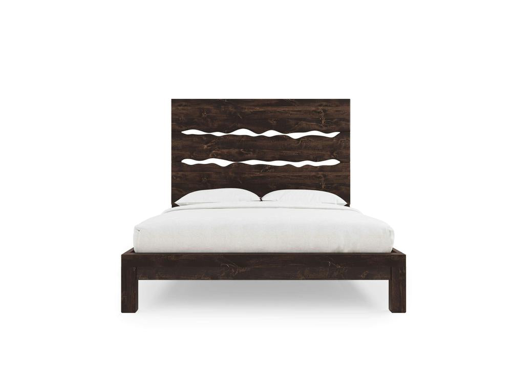 The James+James Live Edge Bed - Tobacco on Alder features a tall headboard with three wave-like cutout designs, a dark brown finish, and comes shown with white bedding and two pillows.