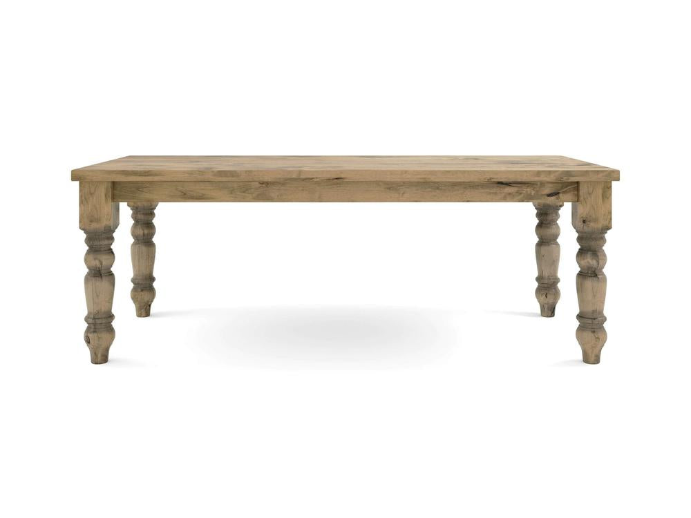 The Baluster Dining Table - Harvest Wheat by James+James features a rectangular wooden top and intricately carved, thick legs. The rustic, natural finish highlights the beautiful wood grain as it stands against a plain white background.