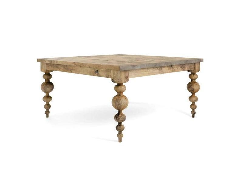 The Olivia Square Dining Table – Harvest Wheat by James+James showcases a smooth tabletop with natural grain patterns. Each of its four legs features decorative, rounded shapes stacked vertically, lending them a sculpted, antique appearance. The table's wood exhibits a light, natural finish.