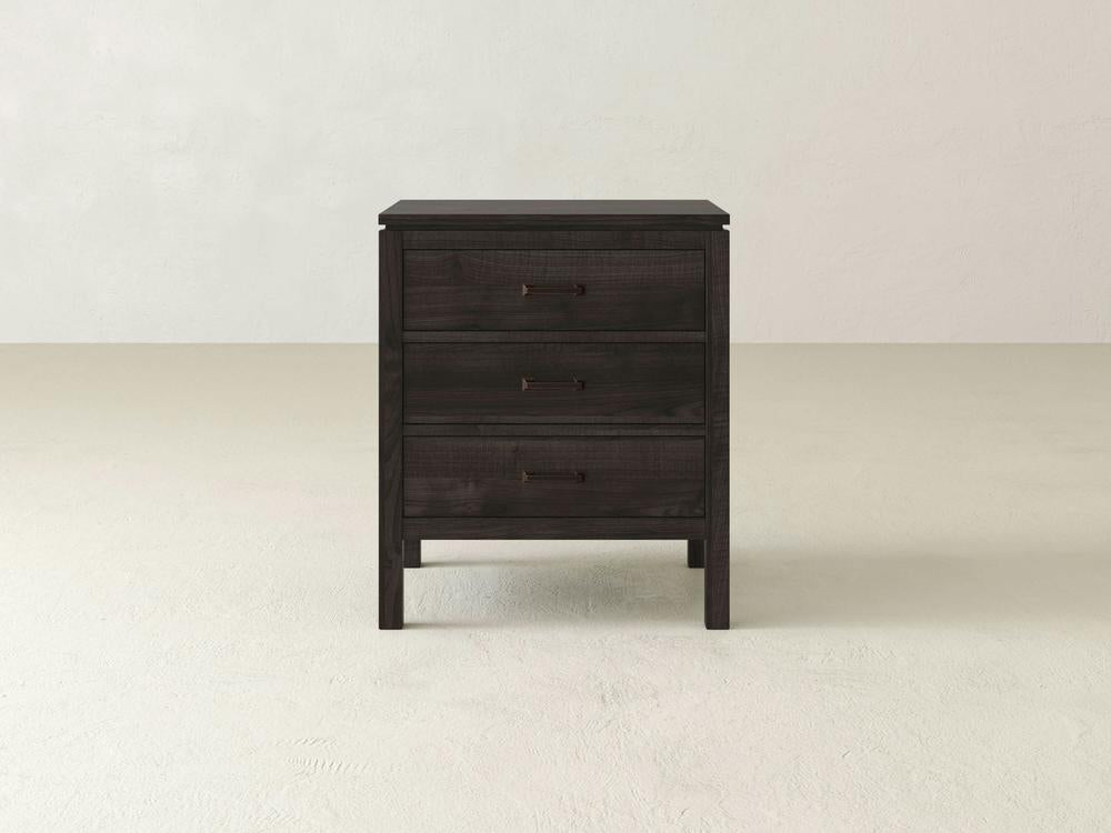 The James & James Jensen 3 Drawer Nightstand, made from solid maple hardwood, rests on a light neutral floor. With three drawers featuring metal handles and clean lines, this minimalist bedside piece stands out against a plain background.