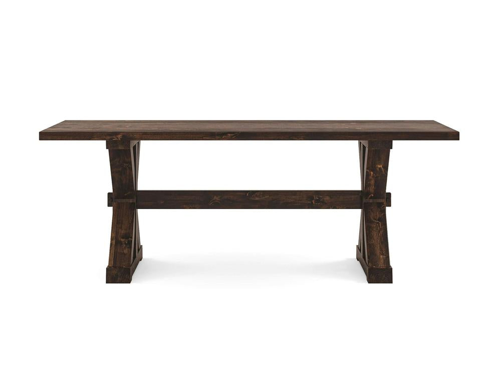 A Trestle Dining Table - Tobacco by James+James with a sturdy, rectangular top and angled, trestle-style legs connected by horizontal support beams. The table has a rustic finish and is set against a plain white background.