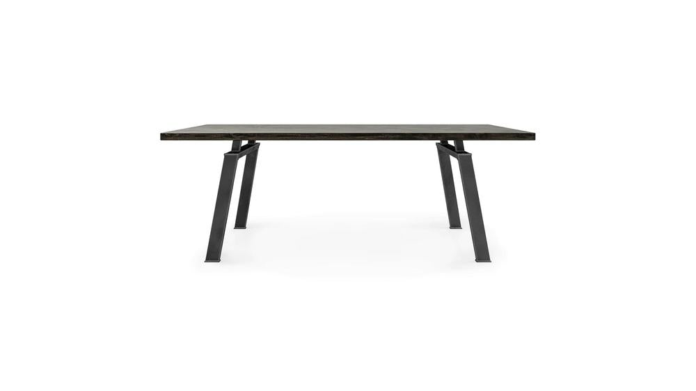 The Fulton Dining Table - Charred Ember by James+James is a modern rectangular table featuring a dark, reflective surface and minimalist black metal legs, set against a white background. Its sleek and contemporary design is perfect for dining or workspace use.