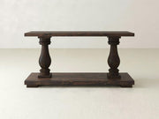 The Vivien Sofa Table in Tobacco by James+James features a wooden, rectangular tabletop and base connected by two ornate, carved baluster-style legs. Its simple and elegant design is perfect for various home decor styles.
