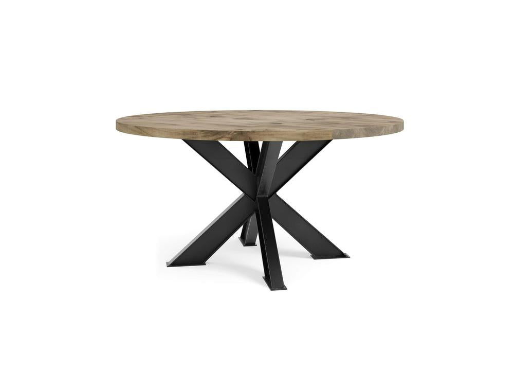 Introducing the Shiloh Round Dining Table in Harvest Wheat by James+James, a contemporary and minimalistic piece featuring a thick, light-colored wooden tabletop and a modern black metal base. The base showcases four angular legs arranged in an intersecting pattern.