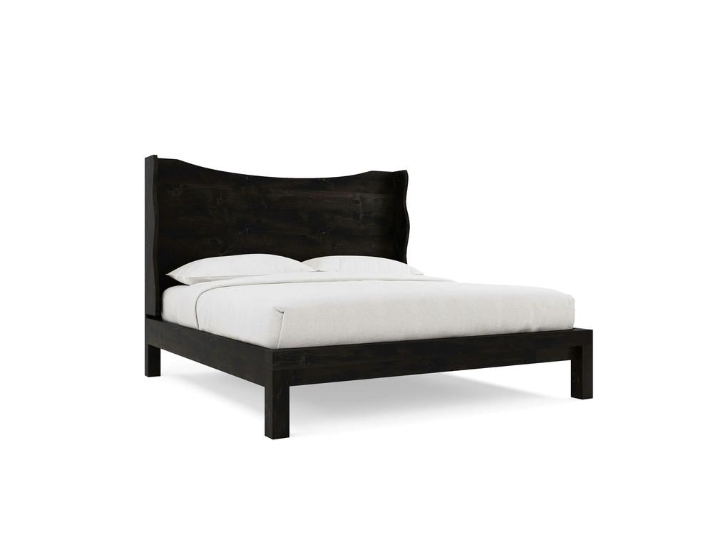 The Harlow Bed by James+James features a charred ember alder frame and a high, wavy headboard, paired with white bedding and pillows, displayed against a plain white background.