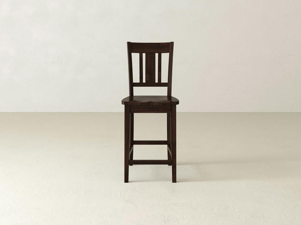 A William Stool by James & James, with a dark brown finish, is set against a light backdrop. Its slatted back and sturdy design bring timeless sophistication, seamlessly complementing any home decor.