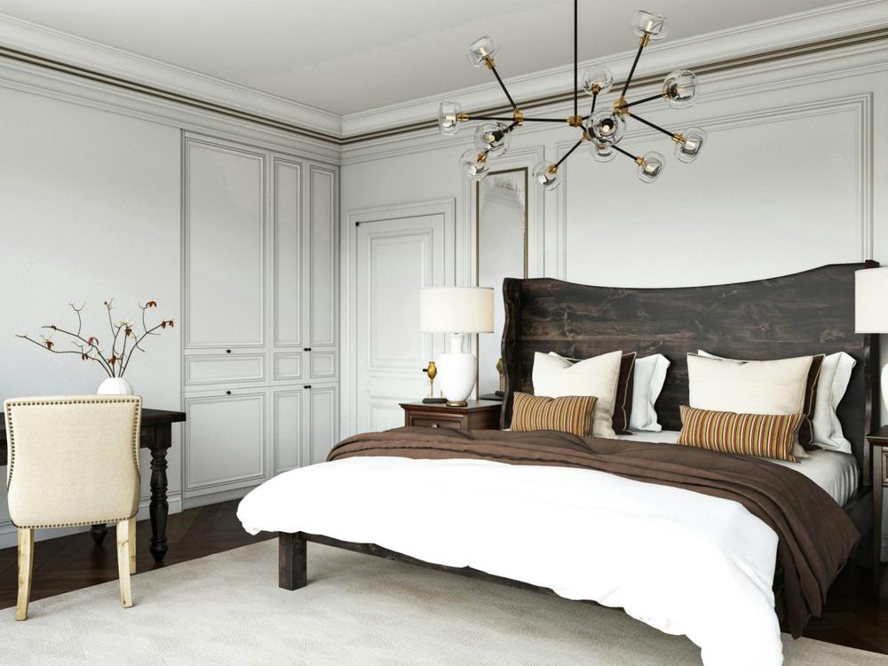 Elegant bedroom featuring the Harlow Bed in Charred Ember on Alder by James+James, white bedding, brown accents, a modern chandelier, built-in white wardrobes, a desk with beige chair, and minimalist decor.