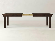The Farmhouse Expandable Dining Table - Tobacco by James+James is shown in an expanded state, revealing its extension mechanism in the middle. The table features four sturdy legs and a simple, minimalist design. The plain, light-colored background enhances the dark wood's details and highlights the table's features.