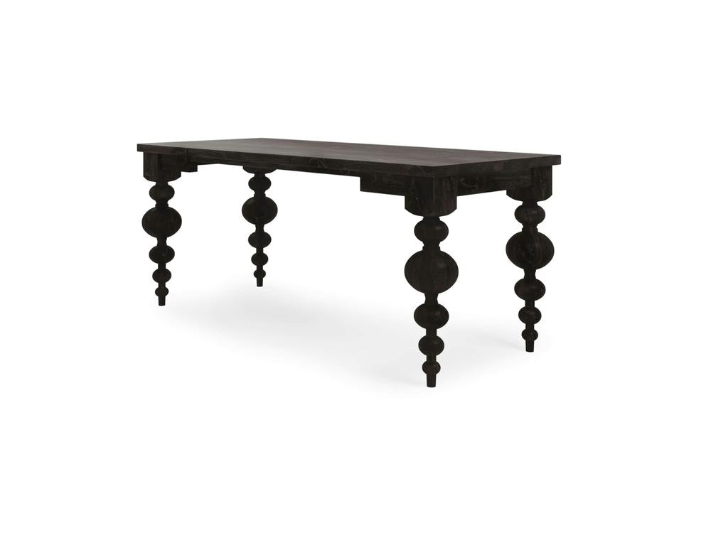 The Olivia Desk - Charred Ember from James+James is a dark wooden table showcasing intricate, sculpted legs with an artistic, spherical design. It features a rectangular top and is set against a plain white background. This piece elegantly combines traditional craftsmanship with modern aesthetics.