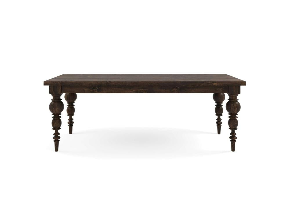 The Bailey Dining Table - Tobacco by James+James is a dark wooden table with a rectangular shape and four intricately carved legs. With its rustic finish and sturdy appearance, it is suitable for dining or as a large work surface. It is placed against a plain, white background.