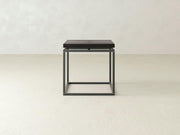 The Floating Top End Table - Charred Ember by James+James is a minimalist black metal side table featuring a square frame and a wooden top, set against a plain, light-colored background.