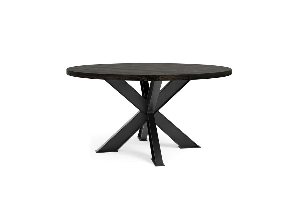 The Shiloh Round Dining Table - Charred Ember by James+James features a round, dark wooden top and is supported by a sleek black metal base with an intersecting cross design. This table, showcasing a modern, minimalist style, is set against a white background.