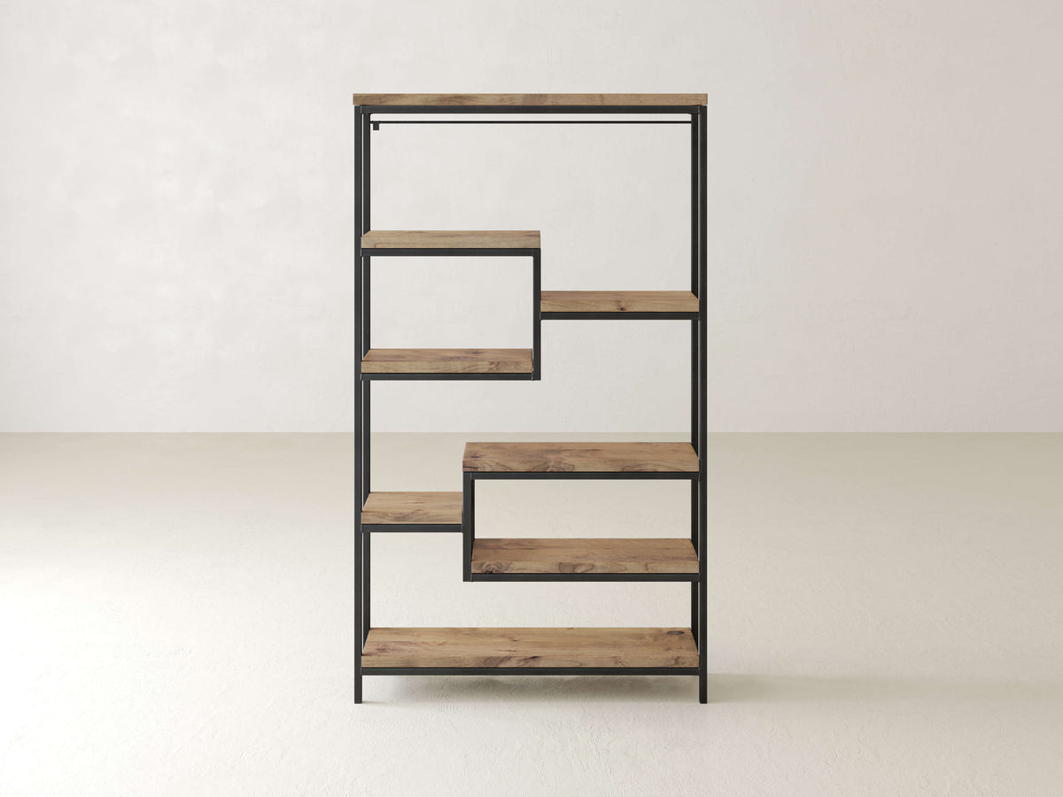A minimalist, tiered wooden bookshelf with a black metal frame. It features five staggered shelves, creating an asymmetrical design, and stands against a plain, light-colored wall and floor.