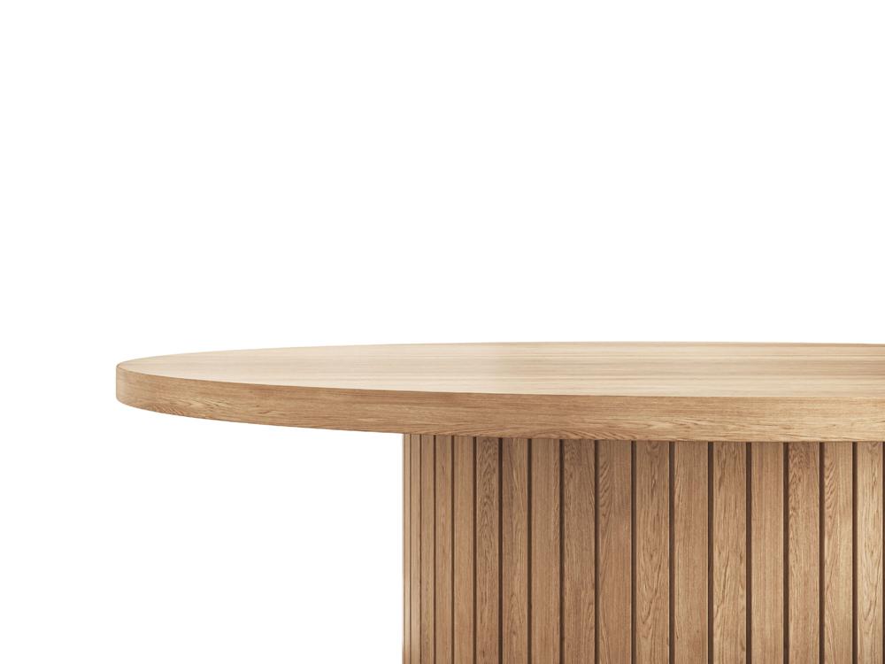A close-up view of the Arthur Dining Table - Satin by James+James showcases its smooth, round tabletop. The base features a vertical slat design, giving it a modern and stylish appearance. The wood has a natural finish, highlighting its grain and texture against a white background.