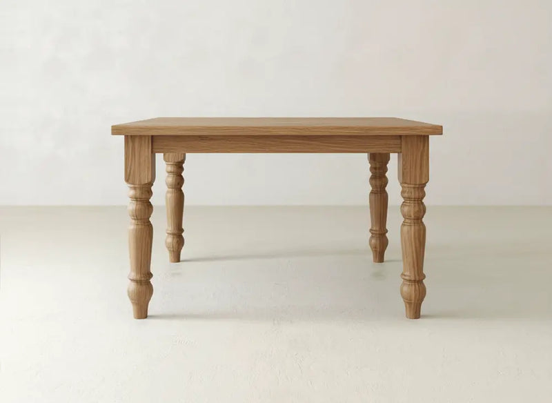 The Fulton Corner Desk - Tuscany by James & James features a rectangular wooden top and four carved, spindle-shaped legs, displayed against a plain, light-colored background.