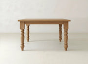 The Fulton Corner Desk - Tuscany by James & James features a rectangular wooden top and four carved, spindle-shaped legs, displayed against a plain, light-colored background.