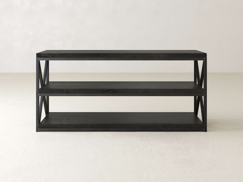 A black three-tiered metal shelf stands against a plain white background. The shelf features an open design with X-shaped supports on the sides, and each tier is a solid, flat surface.