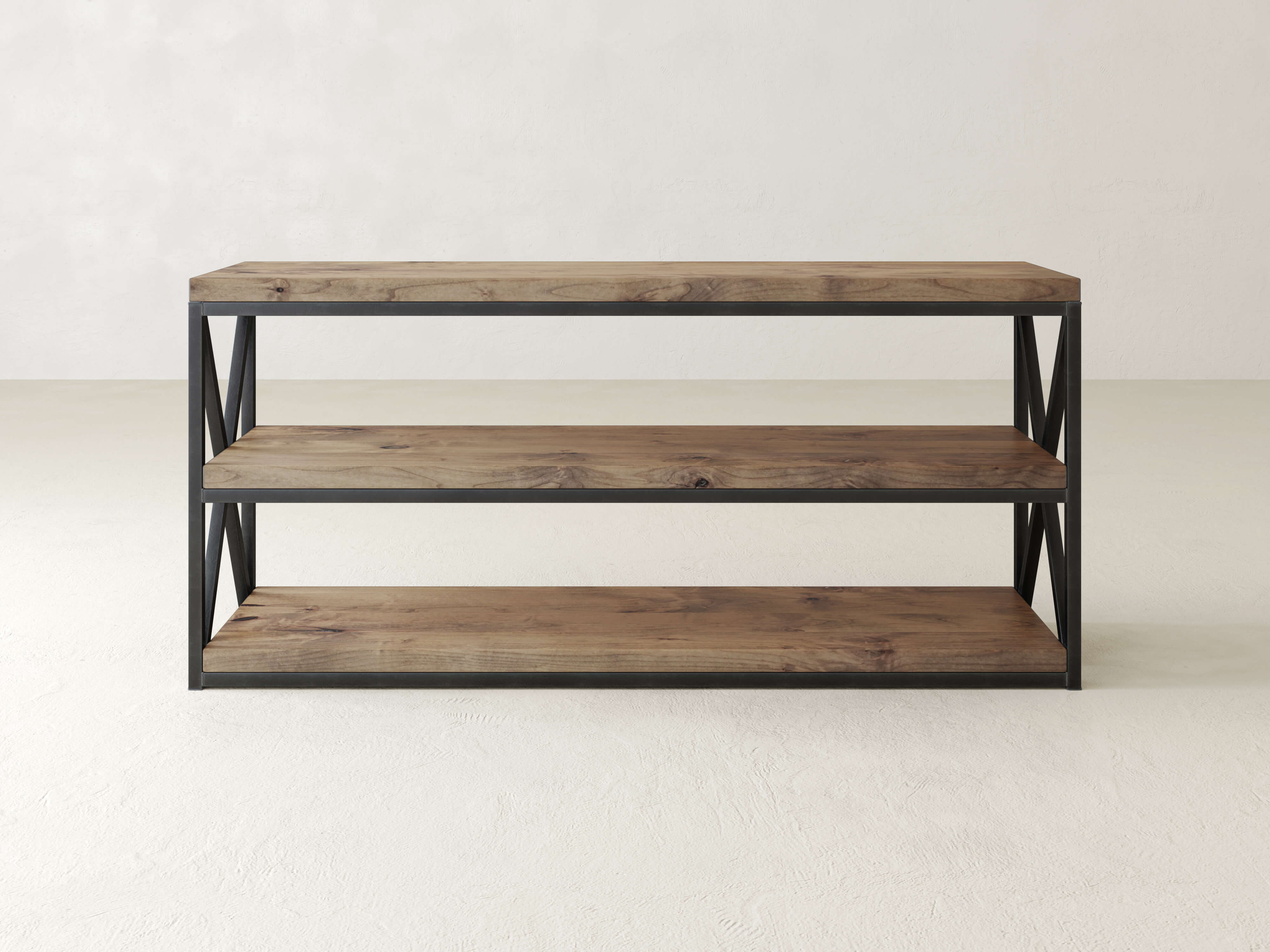 A three-tier wooden shelf with black metal frame and open sides, featuring X-shaped metal details. The shelves are empty, and the unit stands on a light gray floor against a light gray wall.