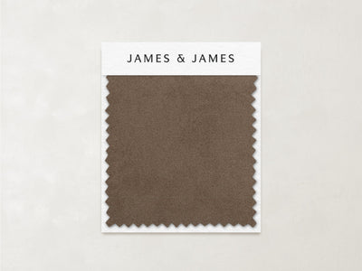 A rectangular caramel-toned "Latte - Velvet Swatch" from James+James, with zigzag edges, rests on a branded card against a light textured background, showcasing its soft texture.
