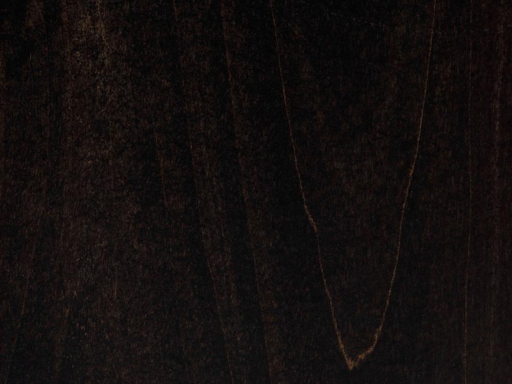 The Heirloom Expandable Dining Table - Charred Ember by James+James features a dark, textured surface that resembles natural wood. The grain and subtle variations in color create intricate patterns, with lighter and darker streaks running vertically across the table. The overall tone is deep and rich, adding a sense of depth to its appearance.