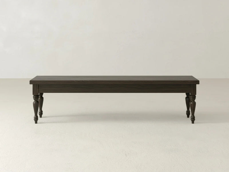 The Chateau Bench - Espresso on Oak by James & James features a simple, classic design with turned legs and stands out against a plain, light-colored wall and floor.