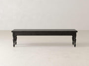 Against a plain white background stands the Chateau Bench by James & James, a long dark wooden piece with carved legs. This handcrafted bench offers a simple, classic design and four decorative legs, perfect for adding elegant dining seating that blends style and function.