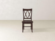 A wooden chair with a dark brown finish stands against a plain white background. The chair features a crisscross backrest design, a flat seat, and four straight legs.