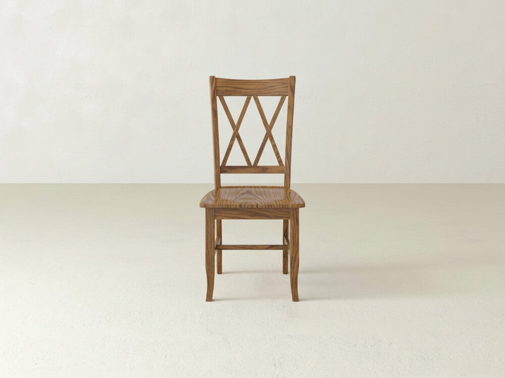 The James+James Double X-Back Dining Chair showcases timeless elegance with its wooden X-shaped backrest, shown here on a light floor against an off-white wall.