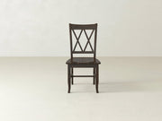 A James+James Double X-Back Dining Chair in dark wood stands out in an empty room with light walls and floor, radiating timeless elegance.