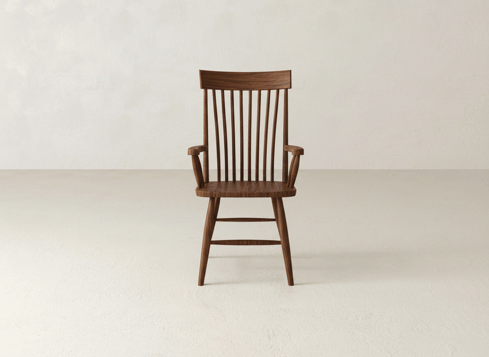 The Eleanor Arm Dining Chair by James+James, featuring a high, narrow slatted backrest, armrests, and four legs, stands on a light-colored floor against a plain off-white wall.