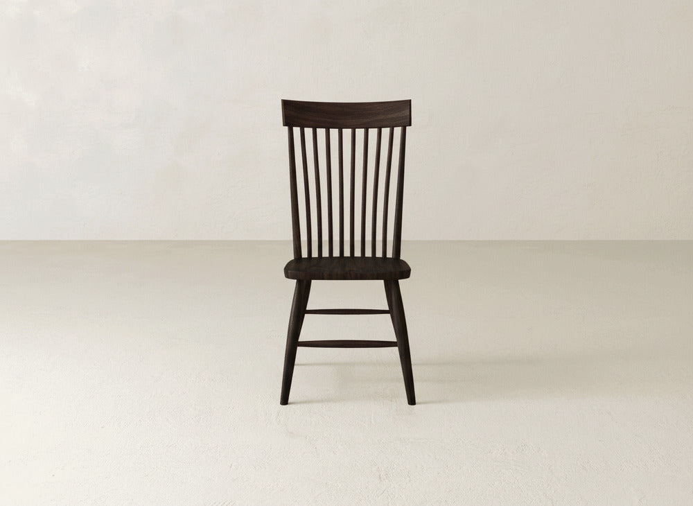 The Eleanor Side Dining Chair by James+James features a dark solid wood build with a high, narrow slatted backrest and straight legs, shown centered on a light floor against a plain pale wall.